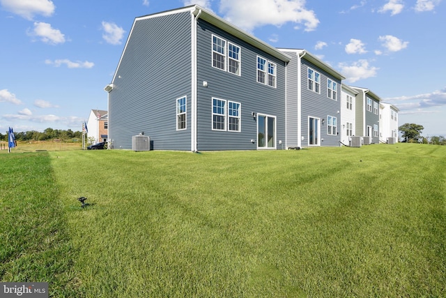 rear view of house with a lawn and central AC unit