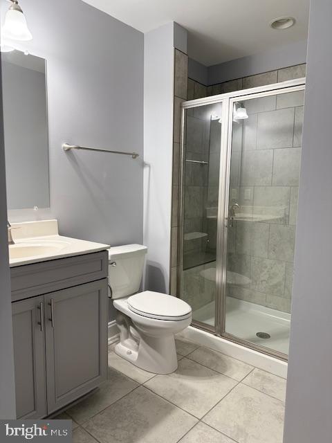 bathroom with tile patterned floors, vanity, toilet, and a shower with shower door