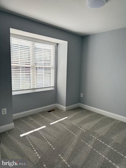 unfurnished room with dark colored carpet