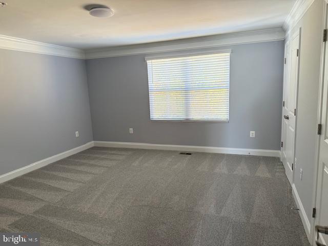 spare room with dark colored carpet and ornamental molding