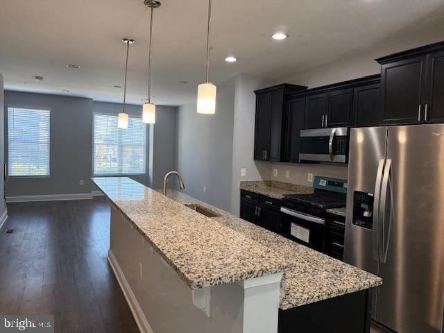 kitchen with pendant lighting, an island with sink, stainless steel appliances, and sink