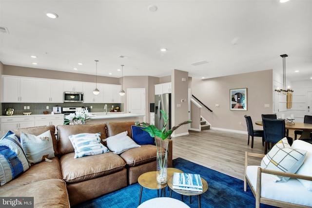 living room featuring a notable chandelier and light wood-type flooring