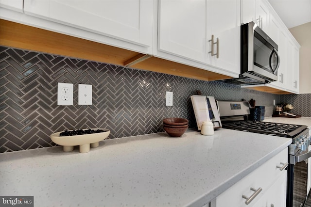 kitchen with decorative backsplash, white cabinets, and appliances with stainless steel finishes