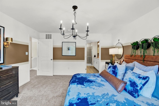 bedroom with light carpet, a chandelier, and ensuite bathroom