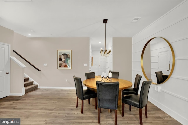 dining area with light hardwood / wood-style flooring and an inviting chandelier