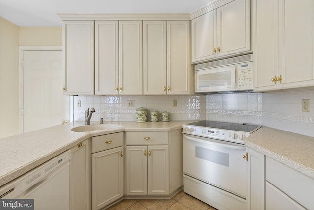 kitchen featuring sink, white appliances, light tile patterned floors, cream cabinets, and decorative backsplash