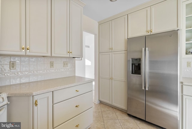 kitchen featuring stainless steel refrigerator with ice dispenser, light tile patterned floors, and backsplash