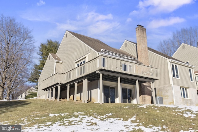 snow covered house with a wooden deck and a lawn