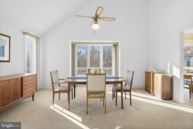 dining space with ceiling fan, plenty of natural light, high vaulted ceiling, and light carpet