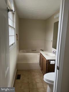 bathroom featuring vanity, toilet, and a tub