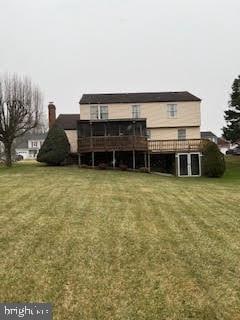 back of property with a deck and a lawn