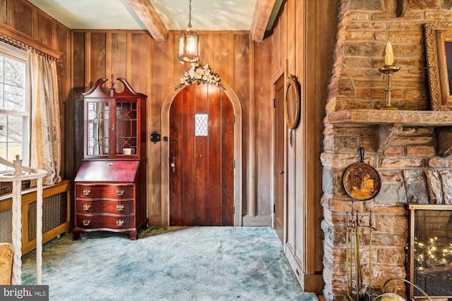 entryway featuring carpet, beam ceiling, and wooden walls