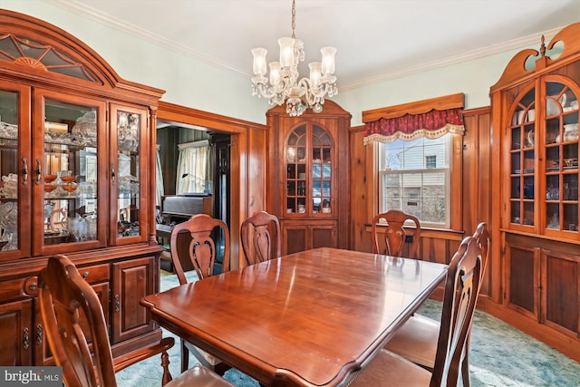 carpeted dining space featuring ornamental molding and a chandelier