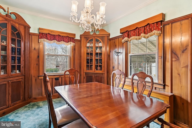 carpeted dining room with crown molding and an inviting chandelier