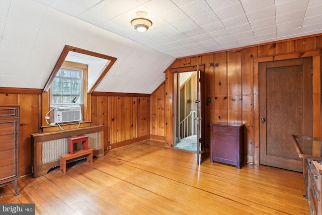 bonus room featuring cooling unit, light hardwood / wood-style floors, wooden walls, and vaulted ceiling