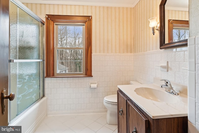 full bathroom featuring vanity, tile patterned floors, bath / shower combo with glass door, toilet, and tile walls