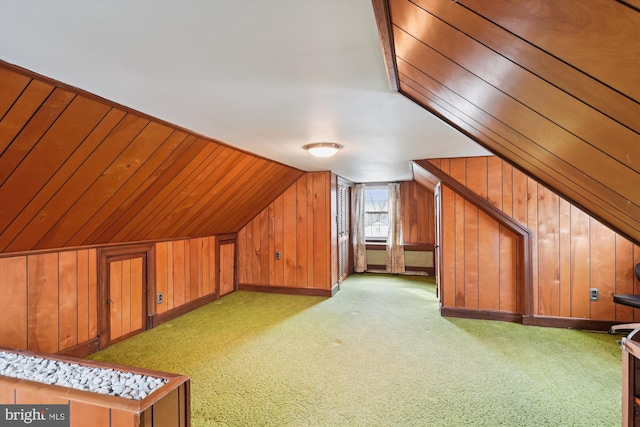 additional living space featuring light colored carpet, lofted ceiling, and wooden walls