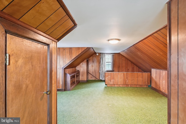 additional living space with light colored carpet, vaulted ceiling, and wood walls