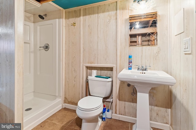 bathroom featuring a shower, tile patterned flooring, wooden walls, and toilet