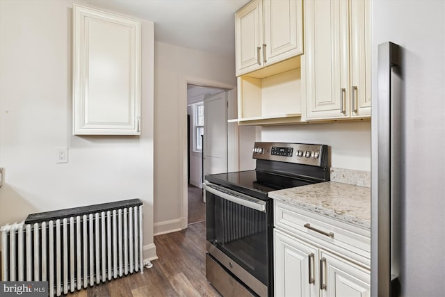 kitchen featuring dark wood-type flooring, light stone counters, radiator, and stainless steel range with electric cooktop