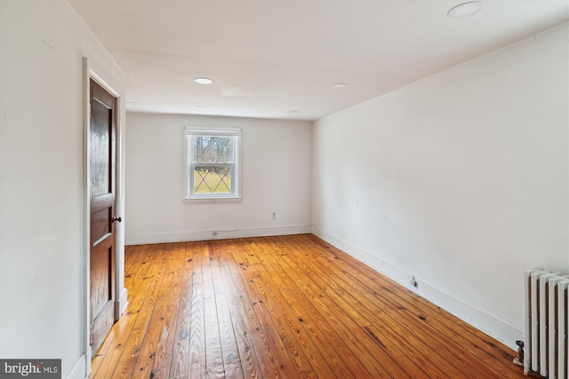 unfurnished room featuring radiator and light hardwood / wood-style flooring