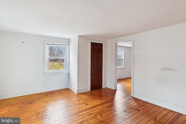 spare room with plenty of natural light and light hardwood / wood-style flooring