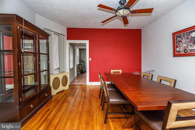 dining area featuring ceiling fan, light hardwood / wood-style floors, and a textured ceiling