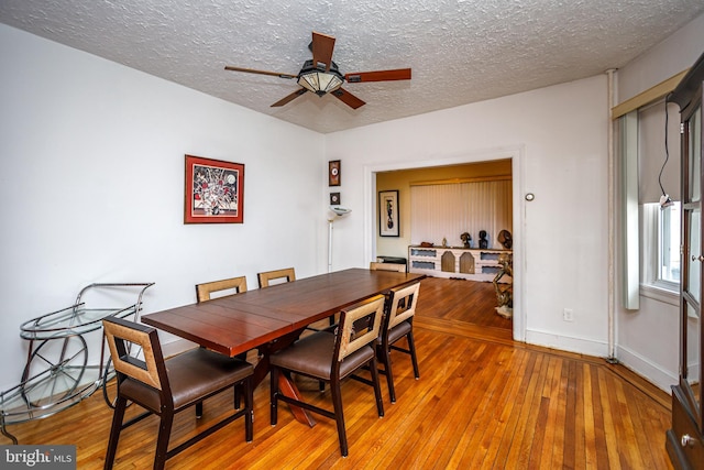 dining space with ceiling fan, a textured ceiling, and light hardwood / wood-style floors