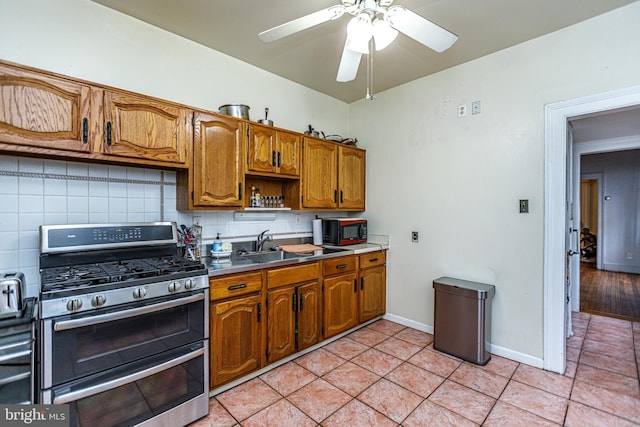 kitchen with tasteful backsplash, sink, double oven range, light tile patterned floors, and ceiling fan