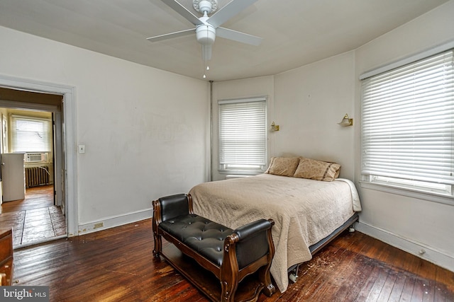 bedroom with dark wood-type flooring, ceiling fan, and radiator