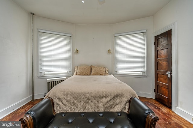 bedroom with dark wood-type flooring, radiator heating unit, and ceiling fan