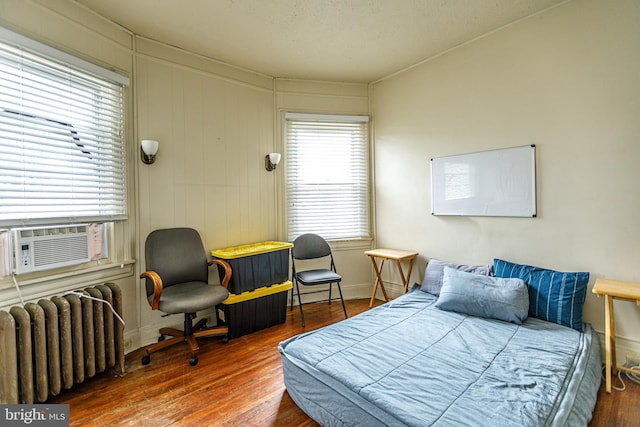 bedroom with hardwood / wood-style flooring, radiator, and cooling unit