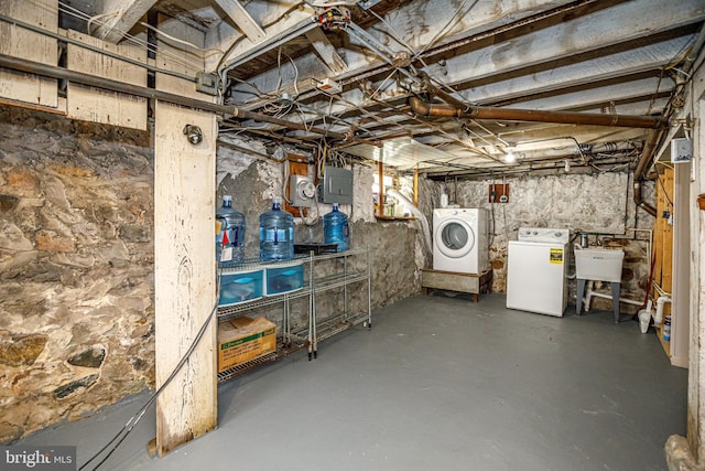 basement featuring washer and dryer, sink, and electric panel