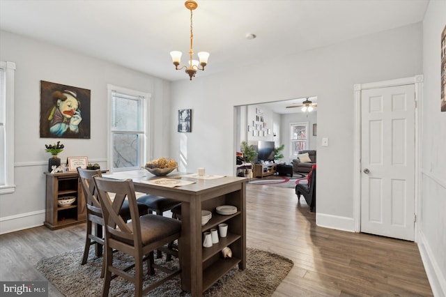 dining area featuring dark hardwood / wood-style flooring and ceiling fan with notable chandelier