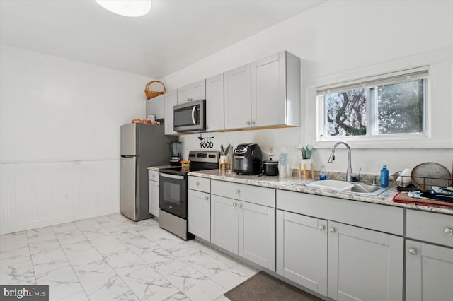 kitchen with light stone counters, sink, and appliances with stainless steel finishes