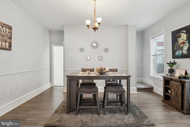 dining area with dark wood-type flooring and a notable chandelier