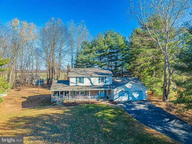 view of front of home with a garage, covered porch, and a front lawn