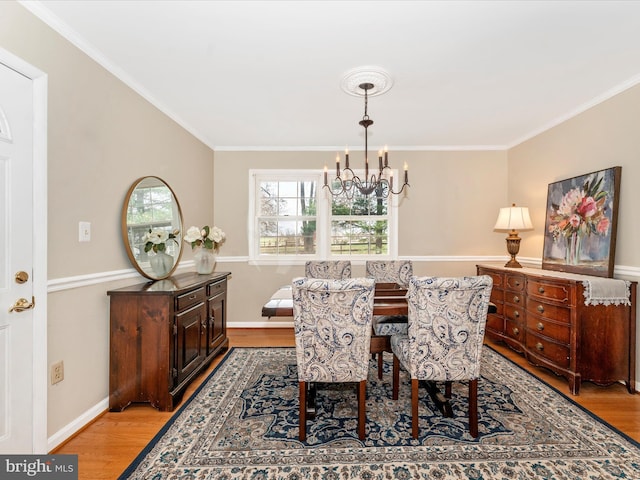 dining space with light hardwood / wood-style flooring, an inviting chandelier, and crown molding