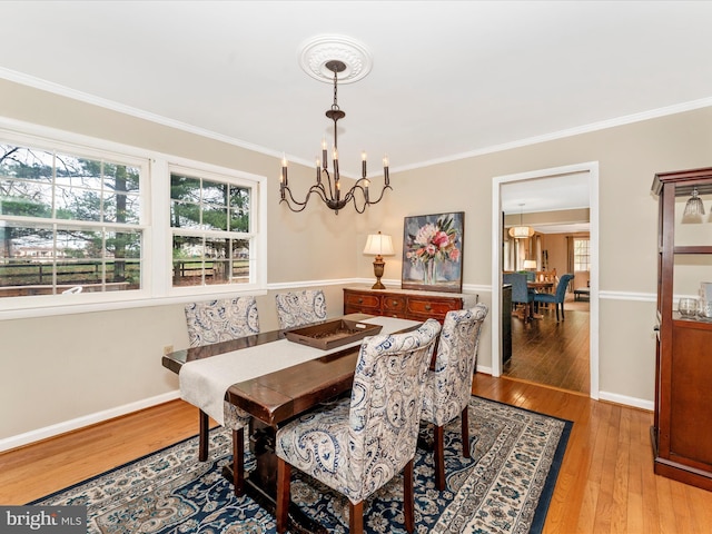 dining space with light hardwood / wood-style flooring, a chandelier, and ornamental molding