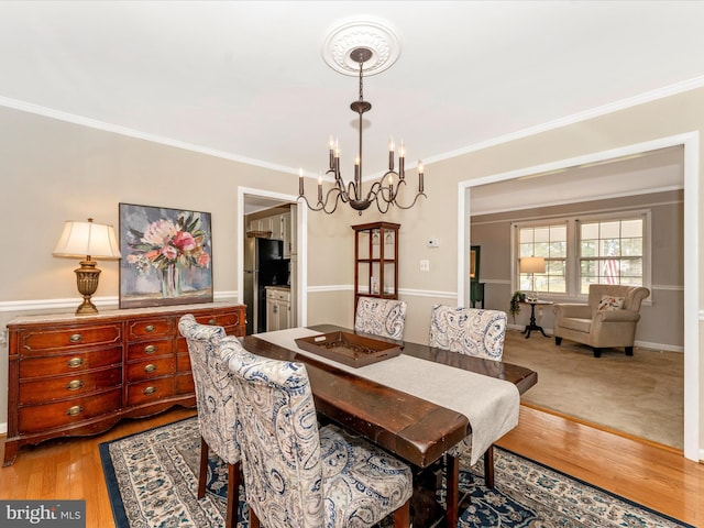 dining area featuring hardwood / wood-style floors, ornamental molding, and an inviting chandelier