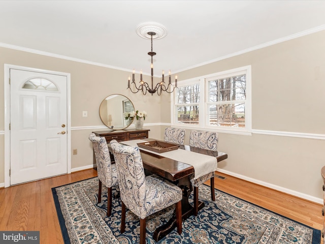 dining space featuring hardwood / wood-style floors, an inviting chandelier, and crown molding