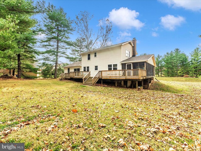 rear view of house featuring a sunroom, a wooden deck, and a lawn