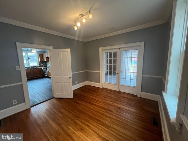 unfurnished room with ornamental molding, dark wood-type flooring, and french doors