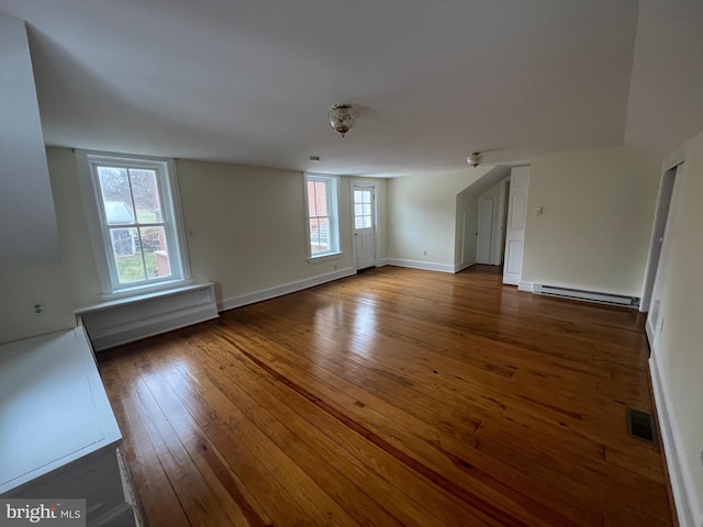 unfurnished room featuring baseboard heating and dark wood-type flooring