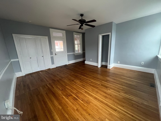 unfurnished bedroom featuring wood-type flooring, two closets, and ceiling fan