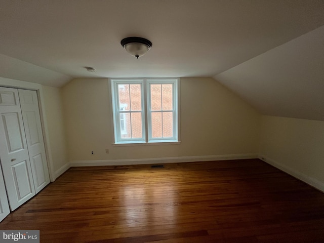 additional living space featuring dark wood-type flooring and lofted ceiling