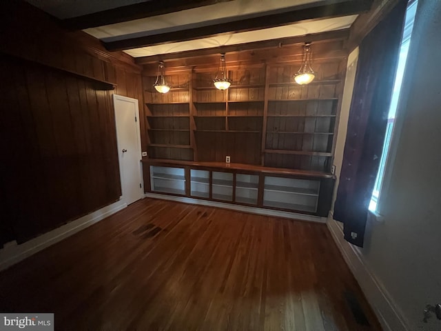 unfurnished room featuring beamed ceiling, wood walls, and dark wood-type flooring