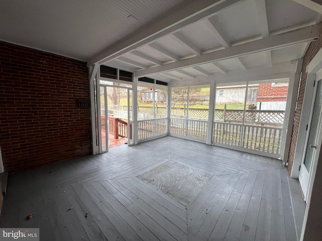 unfurnished sunroom featuring beam ceiling