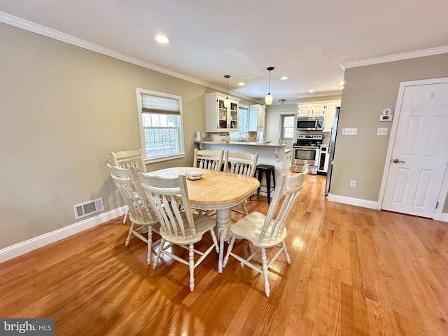 dining room with ornamental molding, sink, and light wood-type flooring