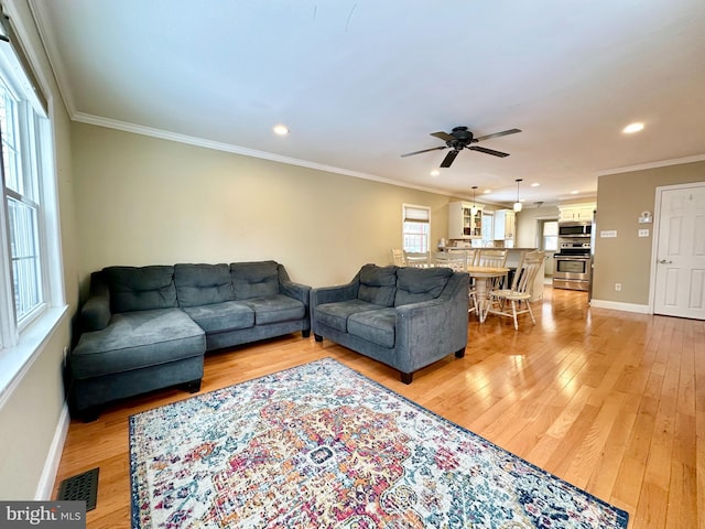 living room with crown molding, ceiling fan, and light hardwood / wood-style floors